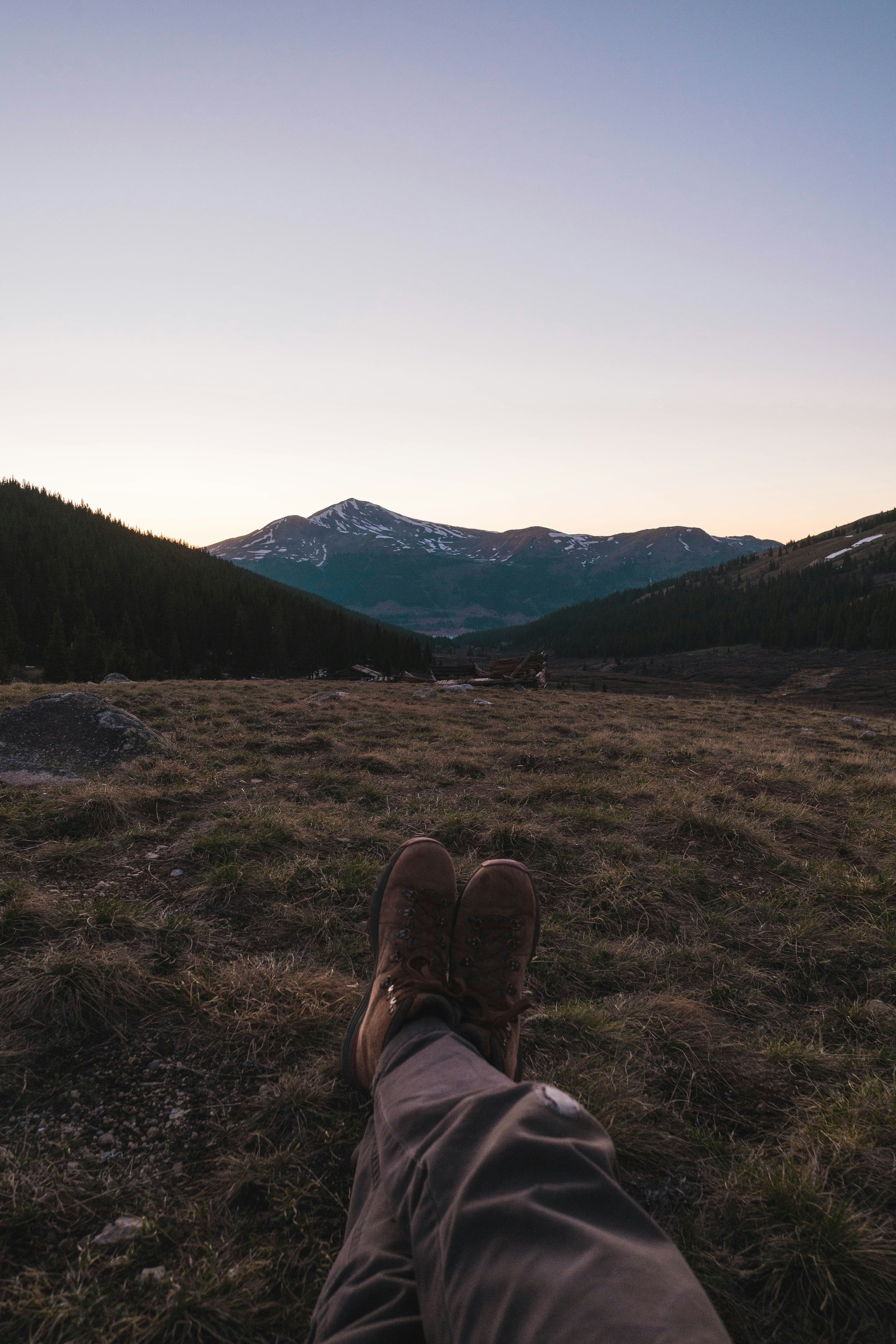 person in brown hiking shoes sitting on brown grass field during daytime